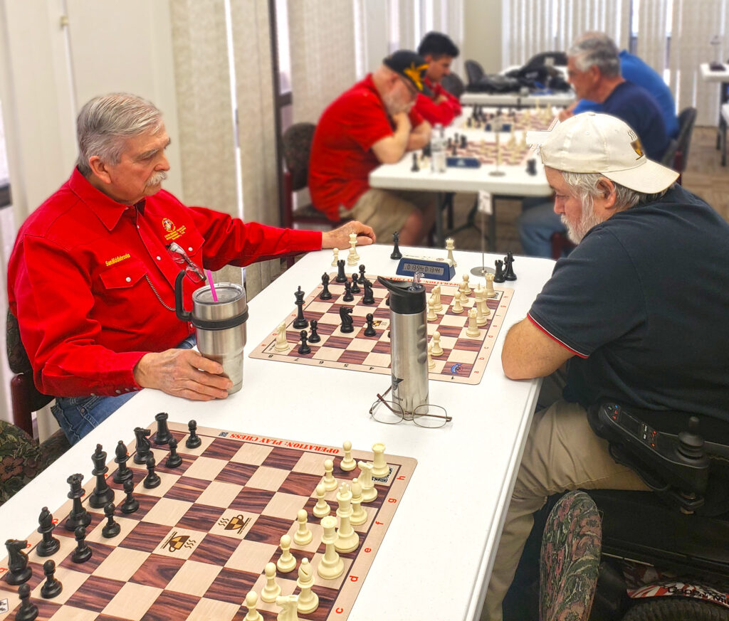 Sam Middlebrooks (left) and Navy veteran Michael Lenox, Chess Vets Co-founder (right), battle in Round 5. Navy fought heroically in what was eventually a Marine Corps victory—photo by Lia Lenox.